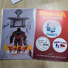 Charger l'image dans la galerie, Two printed comic-related covers or booklets placed side by side on a light wood surface. The left cover is mostly light gray with a black-and-red illustrated figure and multiple signatures; the right cover is red with large yellow text reading 'Dracula The New Chapter' and white circular logos including 'ITC Independent Thinker Comics' and 'Heroes for Kids'.
